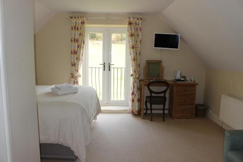 a bedroom with a bed and a desk and a window at The White Horse Inn in Calne