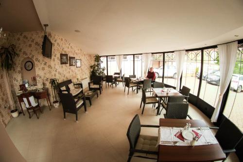 uma sala de jantar com mesas, cadeiras e janelas em Garni Hotel Andric em Sombor