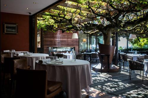 un restaurante con mesas, sillas y un árbol en Le Clos Des Sens en Annecy