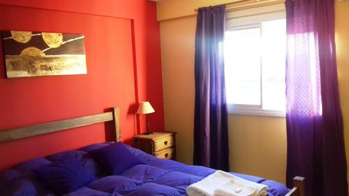 1 dormitorio con 1 cama y una ventana con cortinas moradas en Temporario en Villa Sol en Córdoba