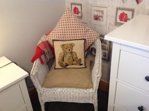 a teddy bear sitting in a chair with a pillow at Dunroamin Self-Catering Apartment in Aviemore