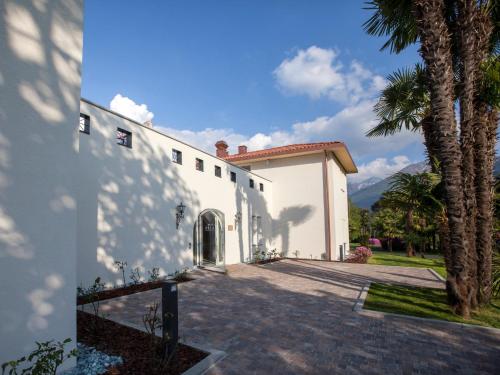 a white building with palm trees in front of it at Delta Resort Apartments in Ascona