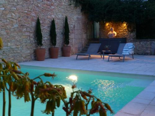 a man sitting in a chair next to a swimming pool at L'Enclos du Micocoulier in Boissières