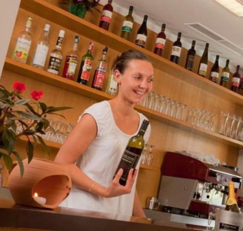 a woman standing behind a counter holding a bottle of wine at Pension Steingarten in Appiano sulla Strada del Vino
