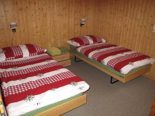 two beds in a room with wooden walls at Haus Sandra in Fiesch