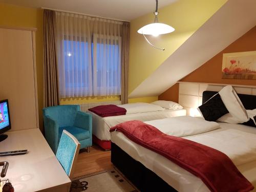 a hotel room with two beds and a chair at Legend Hotel in Biebesheim