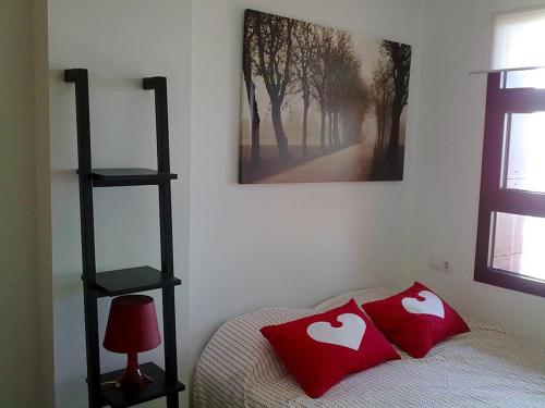 a bedroom with a bed with two red pillows on it at Sierra Nevada piso radiante wifi y parking gratuito in Sierra Nevada