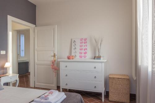 a bedroom with a white dresser and a bed at Palazzo Spada - Attico con terrazza vista fiume in centro in Codigoro