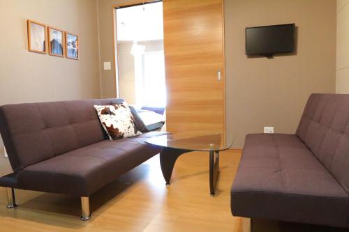 a living room with a couch and a glass table at Chidori Inn Fukuromachi Hiroshima in Hiroshima