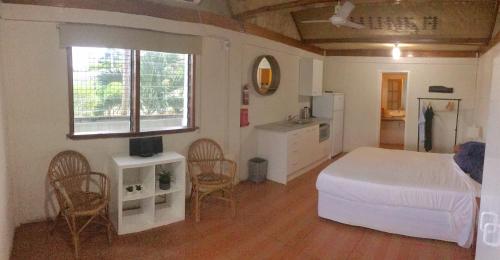 a bedroom with a bed and chairs and a kitchen at Boathouse Apartments in Neiafu