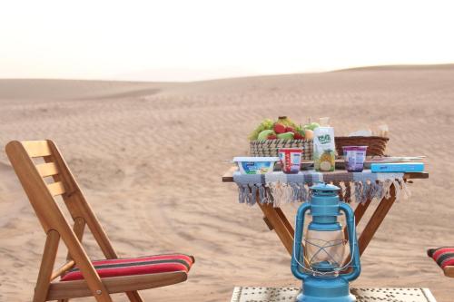 a table in the desert with a basket of fruit at Legend Desert camp in Fulayj al Mashāʼikh