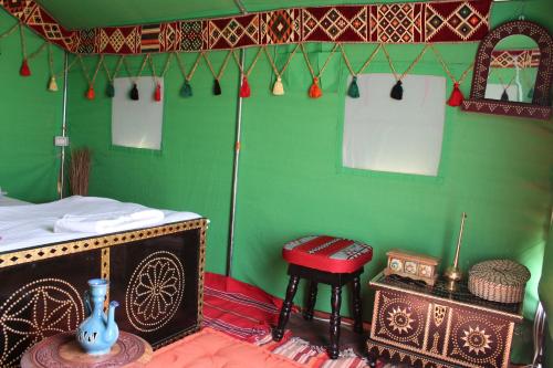 a room with a green wall with a table and a stool at Legend Desert camp in Fulayj al Mashāʼikh