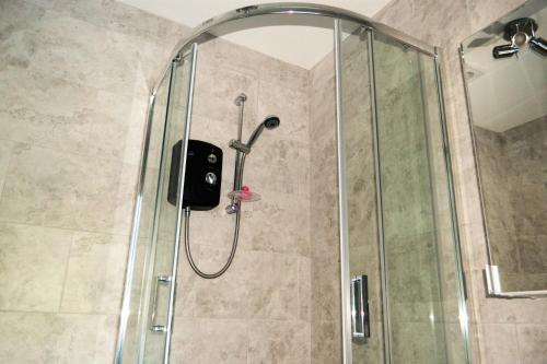 La salle de bains est pourvue d'une douche avec un pommeau en verre. dans l'établissement Ultra Urban Belfast Apartments, à Belfast