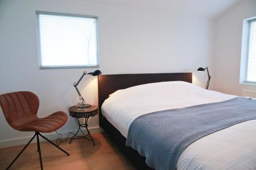 1 dormitorio con 1 cama, 1 silla y 1 lámpara en Residentie De Hoek en Den Dungen