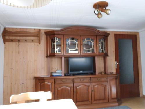 a wooden entertainment center with a television in a room at Ferienwohnung Irmgard in Plein