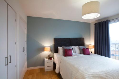 a bedroom with a large white bed with pink pillows at Watford Centre - Luxury Penthouse in Watford