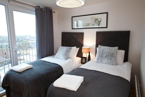 two beds in a hotel room with a balcony at Watford Centre - Luxury Penthouse in Watford