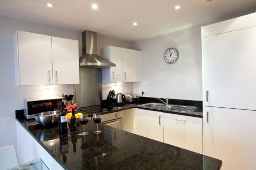 a kitchen with white cabinets and a black counter top at Watford Centre - Luxury Penthouse in Watford