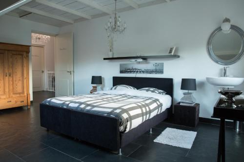 1 dormitorio con cama y espejo en la pared en B&B Van Hunebed Naar Jullie Bed en Schoonoord
