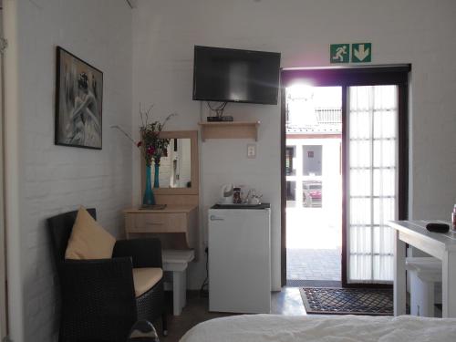 a living room with a kitchen with a television on the wall at Myrtles Retreat in Stilbaai