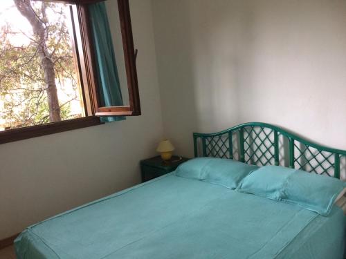 a bedroom with a blue bed with a window at Appartamento in Rudargia Residence in Porto Rotondo