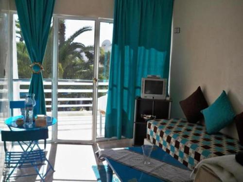ein Wohnzimmer mit einem Sofa, einem Tisch und einem TV in der Unterkunft Residence Tafat in Agadir