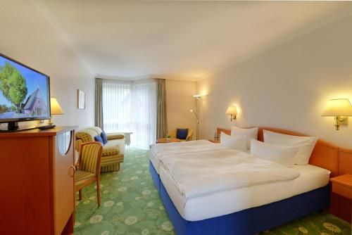 a hotel room with a large bed and a television at Landhotel Zur Eiche in Buxtehude