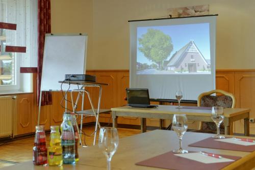 a room with two tables with wine glasses and a screen at Landhotel Zur Eiche in Buxtehude