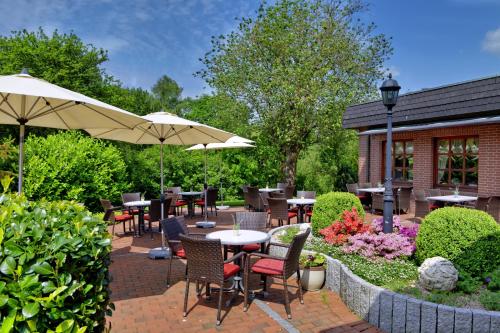 a patio with tables and chairs and an umbrella at Landhotel Zur Eiche in Buxtehude