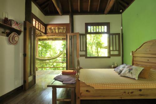 a bedroom with a bed and two windows at Casa Sertão de Camburi in Camburi
