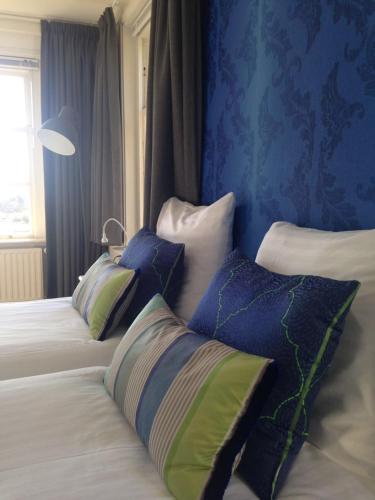 a bedroom with two beds with pillows and a blue wall at The Riverside Logies & Restaurant in Maarssen