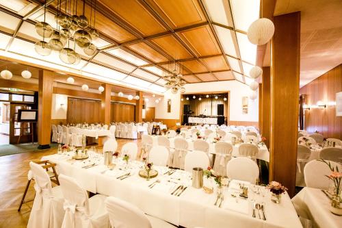 a banquet hall with white tables and white chairs at Landhotel Zur Eiche in Buxtehude
