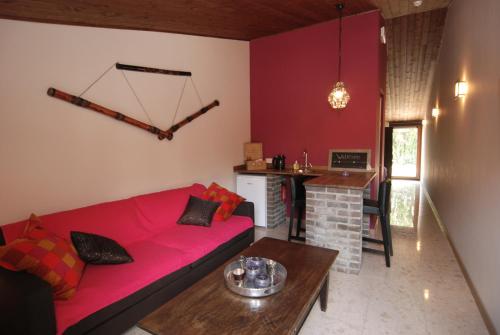 a living room with a red couch and a table at Het Schalks Genot in Poppel