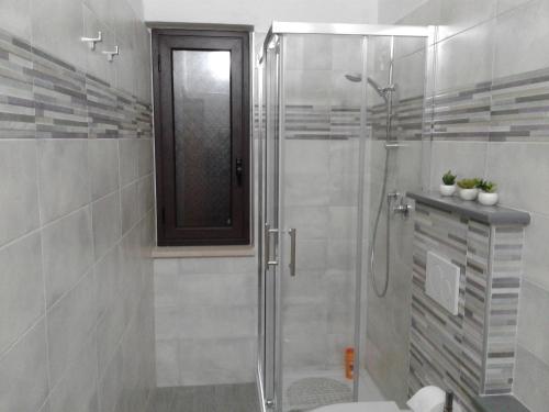 La salle de bains est pourvue d'une douche avec une porte en verre. dans l'établissement B&B Domus Tiberio, à Pizzo