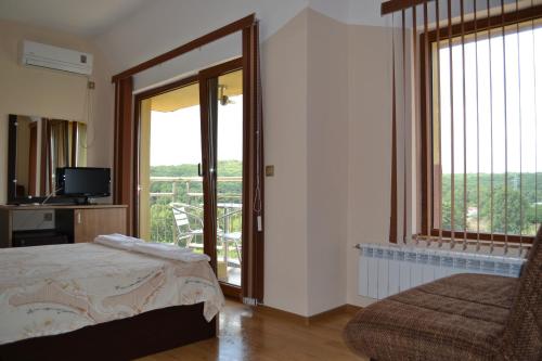 a bedroom with a bed and a sliding glass door at Family Hotel Saint George in Sinemorets
