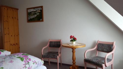 a bedroom with two chairs and a table with a vase of flowers at Jägerheim Löbsal in Löbsal