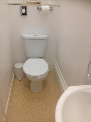 a white bathroom with a toilet and a sink at By The Sea Bed and Breakfast in Eastbourne