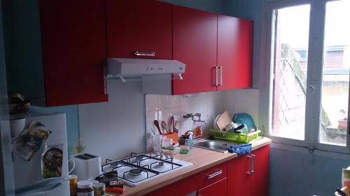 d'une cuisine avec des placards rouges, un évier et une fenêtre. dans l'établissement Domaine Au charme des Plantes, à Rennes