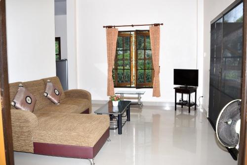 a living room with a couch and a tv at Kate House Bangsaphan in Bang Saphan