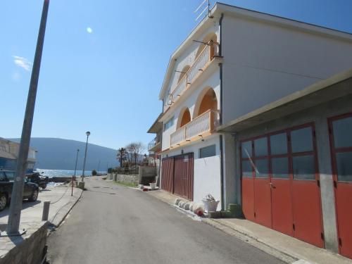 a building with red doors on the side of a street at Stan Apatman Mirela in Herceg-Novi