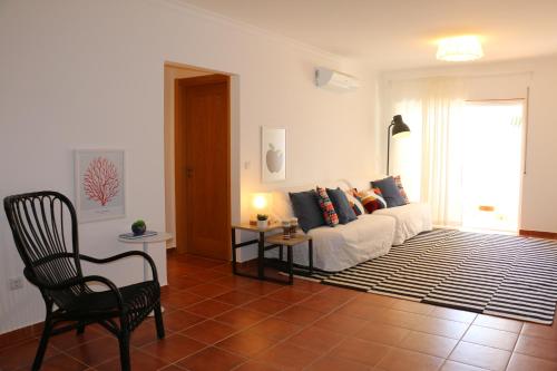 a living room with a white couch and a chair at Apartamento Santa Luzia in Santa Luzia