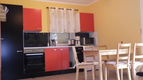 eine Küche mit roten Schränken und einem Tisch mit Stühlen in der Unterkunft Ferienwohnung Am Hegebusch in Altendorf