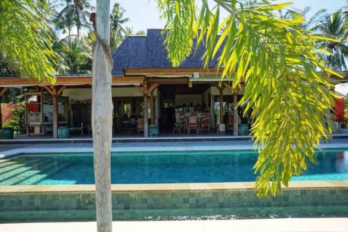 a house with a swimming pool and a palm tree at Villa Taman Kanti in Ubud