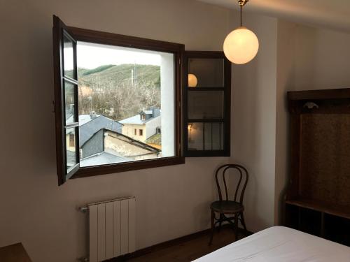 a room with a bed, chair, lamp and window at La Casa Del Reloj in Molinaseca