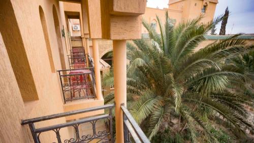an apartment balcony with a palm tree next to a building at Hotel Kasbah Asmaa in Midelt