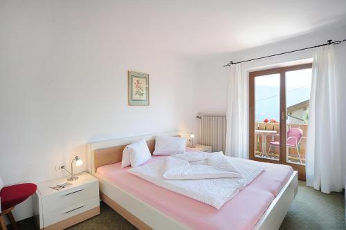 - une chambre blanche avec un lit et une fenêtre dans l'établissement Haus Rosengarten, à Tirolo