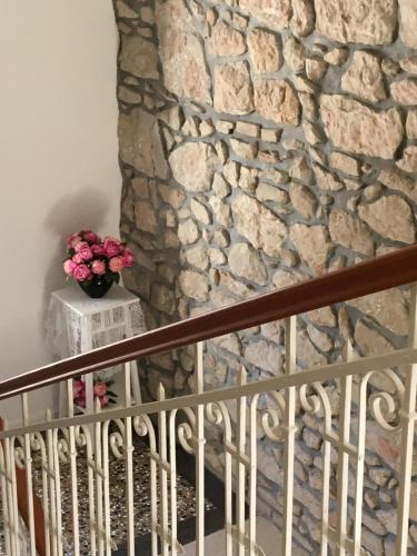 Guest House Villa Dagmar في كريكفينيسا: جدار حجري في غرفة بها إناء من الزهور