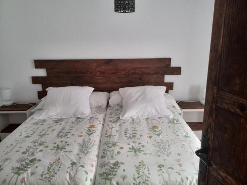 a bedroom with a bed with a wooden headboard at Nido Menas in Torrejón el Rubio