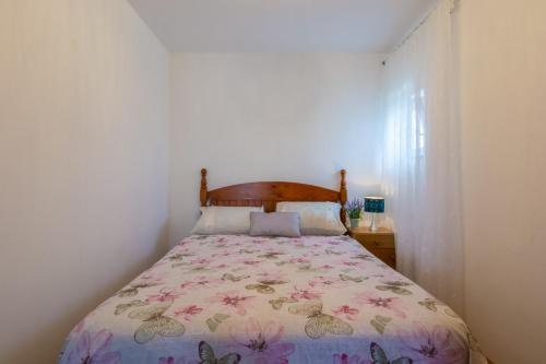 een slaapkamer met een bed met een bloemenbed bij Plavi Apartman in Sukošan
