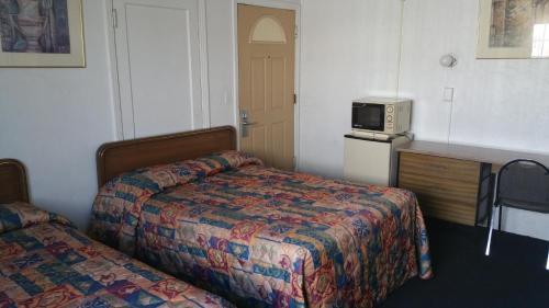 a hotel room with two beds and a microwave at San Joaquin Motel in Merced